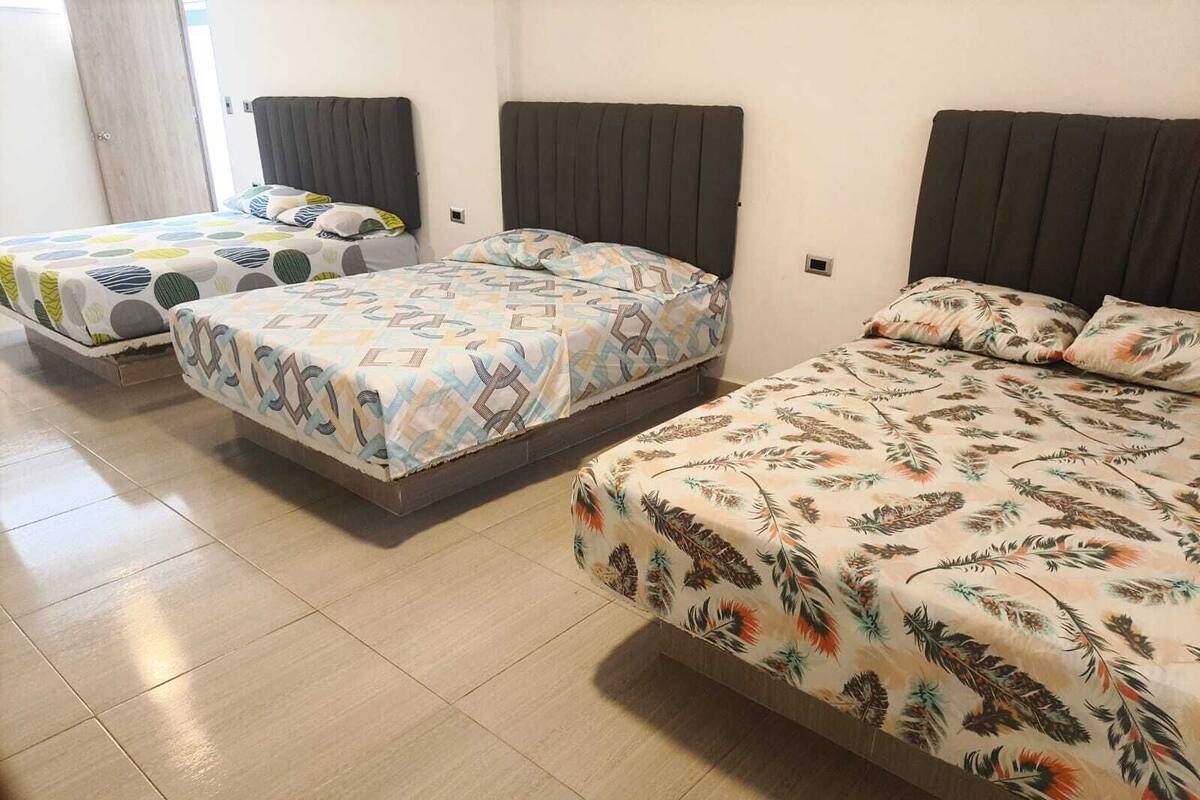 Ein Hotelzimmer mit drei Betten, jedes mit einer anderen gemusterten Tagesdecke.