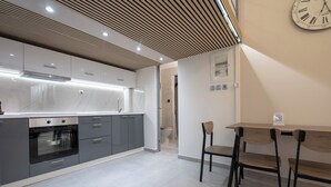 A modern kitchen with grey cabinets, a built-in oven, and a wooden ceiling.