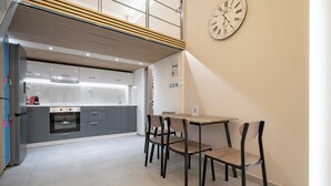 A modern kitchen with grey cabinets, a built-in oven, and a wooden dining table with four chairs.