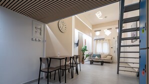 A modern living room with a dining area, a staircase, and a clock on the wall.