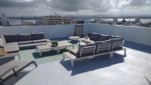 Une terrasse sur le toit aménagée avec un ensemble de canapés, un fauteuil et une petite table.