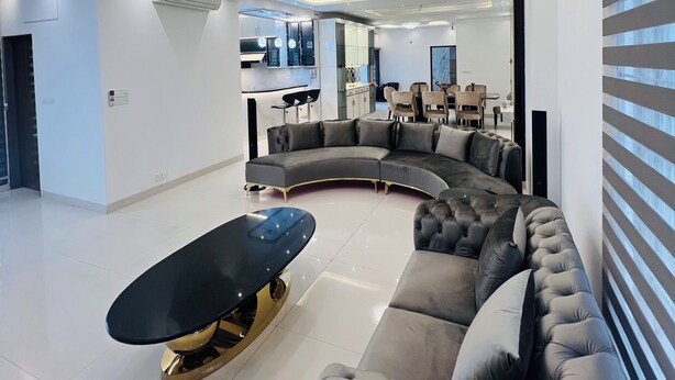 A modern living room with a curved sectional sofa, a black coffee table, and a chandelier. - 10 minutes from airport, Elegant Villa in modern, secure city Basundhara R/S. (Bashundhara R/S)