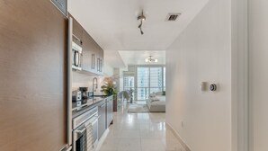 A modern kitchen with stainless steel appliances, a dining area with a table and chairs, and a large window providing a view of the city. - ICON W BRICKELL COZY STUDIO #2205 (Miami)