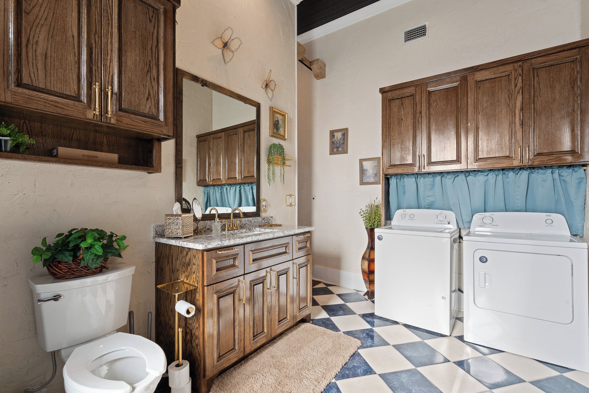 Un baño con gabinetes de madera, un lavamanos, un inodoro y dos lavadoras.