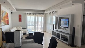 A modern living room with a sofa, chairs, a TV, and a balcony view. - MARINA LUXURY APARTMENT WITH TERRACE EXCEPTIONAL SEA VIEW BEACH 3 MN (Ashdod)