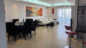 A modern living room with a dining area, a sofa, a coffee table, and a TV. - MARINA LUXURY APARTMENT WITH TERRACE EXCEPTIONAL SEA VIEW BEACH 3 MN (Ashdod)