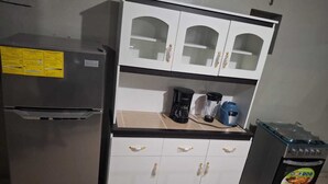 A compact kitchen with a refrigerator, a coffee maker, a blender, and a gas stove. - Spacious apartment (ss)