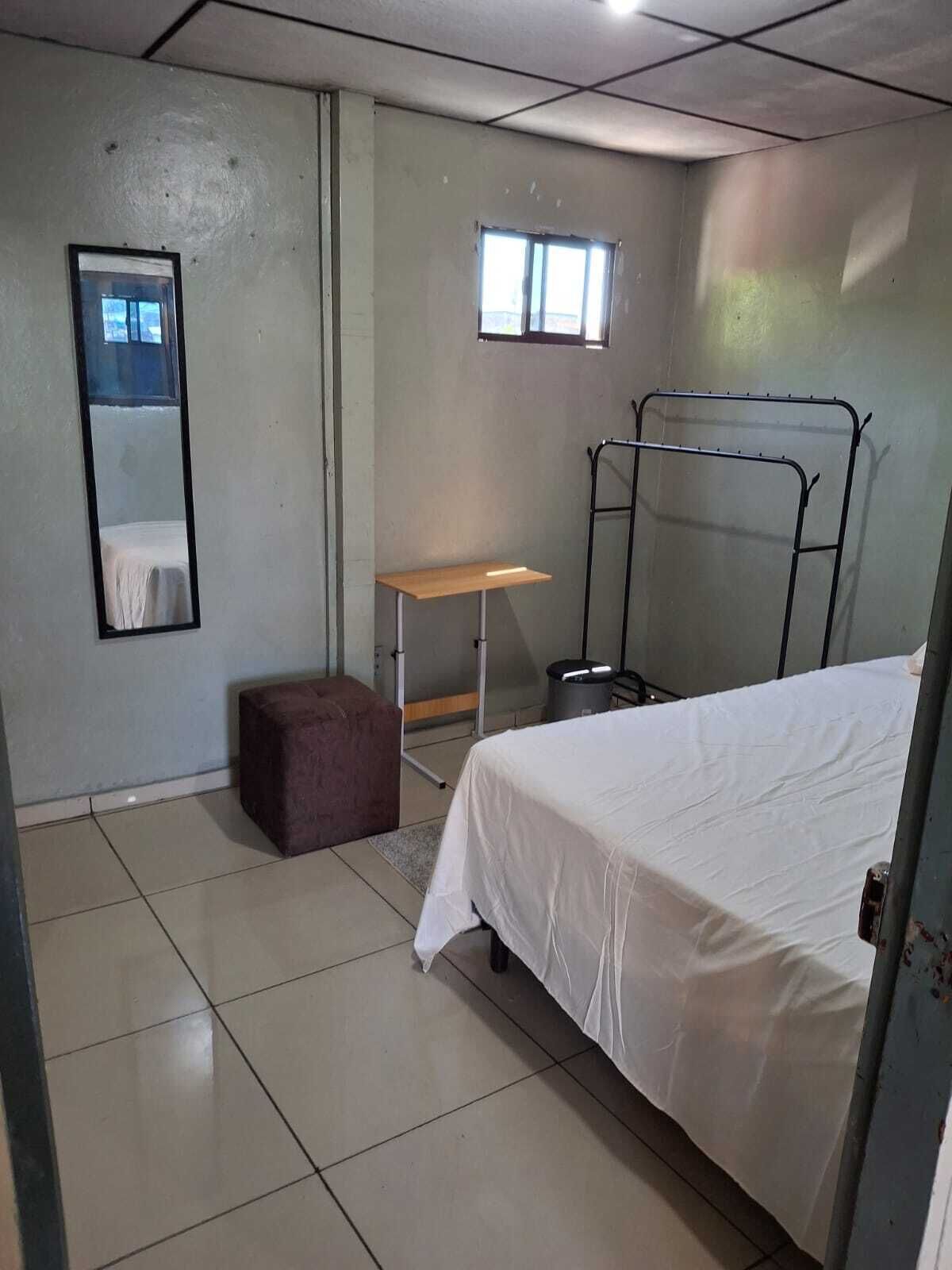 Une petite pièce propre, avec un lit, un bureau, une chaise et un miroir.