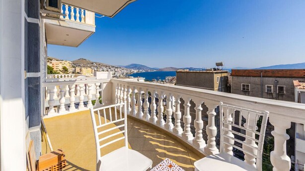 Un balcon avec des balustrades blanches, une vue sur la mer et des bâtiments en arrière-plan.