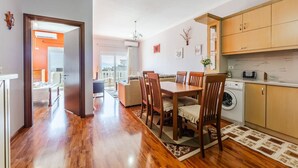 Une cuisine moderne avec des meubles en bois, un coin repas avec une table et des chaises en bois, et une vue sur l’extérieur.