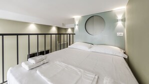 A modern hotel room with a large bed, a circular mirror on the wall, and a balcony with a railing. - Amel's Rooms by PikHost (Tiranë)