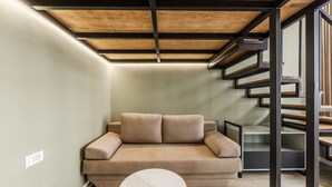 A modern interior with a sofa, a small table, and a staircase. - Amel's Rooms by PikHost (Tiranë)