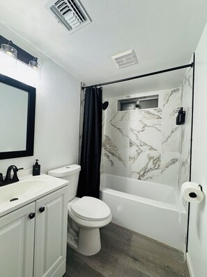 A bathroom with a white sink, toilet, and bathtub.