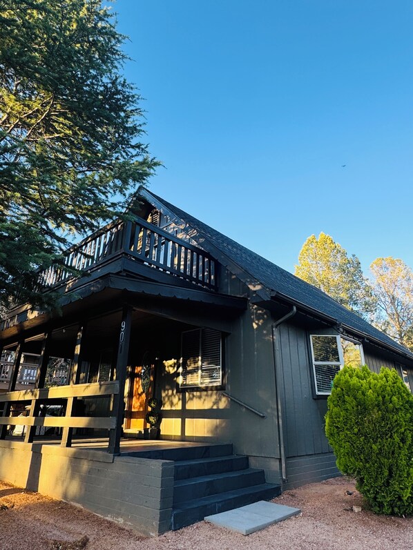 A two-story house with a porch, a small garden, and a clear blue sky.