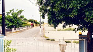 A gated entrance with a white fence, a street view, and a lamp post.