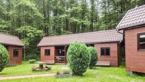 A row of wooden cabins with tiled roofs, surrounded by a forest. Each cabin has a porch and a small garden area. - 1 bedroom gorgeous home in Lazy (Lazy)