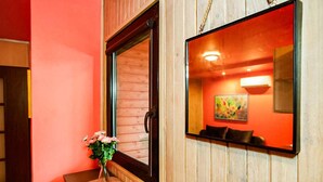 A room with a wooden paneled wall, a large mirror reflecting a colorful painting, and a vase with pink flowers on a small round table. - 1 bedroom gorgeous home in Lazy (Lazy)