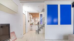 Un intérieur moderne avec un escalier, un coin cuisine et une porte blanche agrémentée de panneaux bleus.
