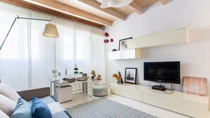 Un salon moderne avec un canapé, une table basse, un téléviseur et une bibliothèque.
