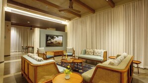 Ein geräumiges Wohnzimmer mit hohen Decken, Holzmöbeln, einem großen Fenster und einem Gemälde an der Wand.