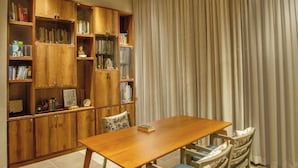 Ein Essbereich mit einem Holztisch und Stühlen, umgeben von Bücherregalen mit Büchern und Dekoration.