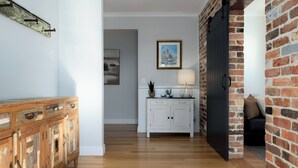 Ein Flur mit einem Holzkabinett, einem weißen Schrank mit Schubladen, einem gerahmten Bild an der Wand und einer schwarzen Tür zu einem anderen Raum.
