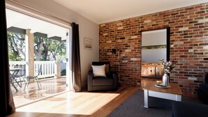Ein Wohnzimmer mit Backsteinwand, einer Couch, einem Couchtisch und Blick auf eine Terrass.