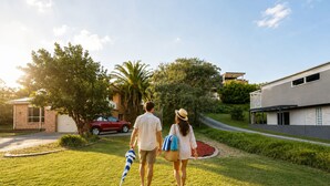 A couple walking on a well-maintained lawn with a modern house in the background. - Culburra Beach B&B Jervis Bay Area Private Room Shared bath with Jacuzzi Pool AC (Culburra Beach)