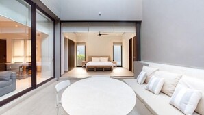 A modern bedroom with a large bed, a round dining table, and a sofa with pillows.