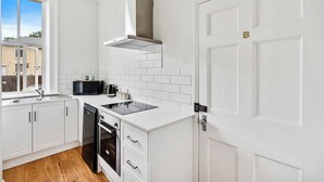 Una cocina moderna con armarios blancos, una estufa negra y una ventana que ofrece vistas al exterior.