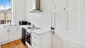 A modern kitchen with white cabinetry, a black stove, and a window providing a view of the outside.