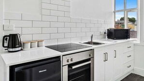 Een moderne keuken met witte kasten, een zwart inductiefornuis, een roestvrijstalen spoelbak en een vaatwasser van Hisense.