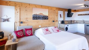 A cozy bedroom with a bed, a nightstand, and a wooden wall with a mountain painting.