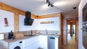 A modern kitchen with wooden beams, a built-in washing machine, a dishwasher, and a coffee maker.