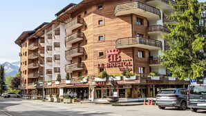 A multi-story hotel with wooden balconies and a sign for 'Le Bristol Villas'.