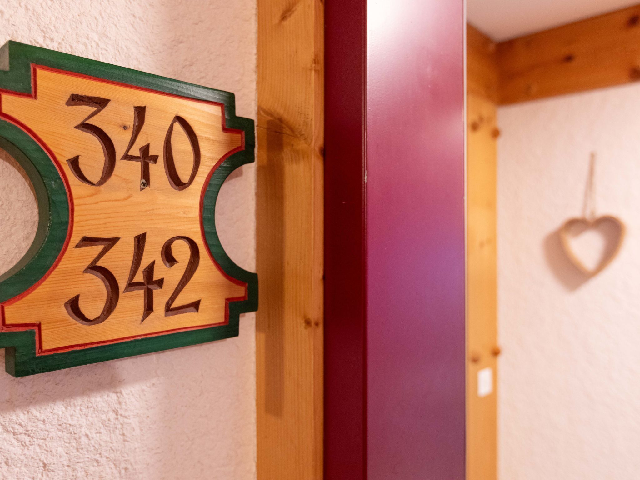 Un letrero de madera con los números 340 y 342, montado en una pared, con una decoración en forma de corazón colgando en la pared contigua.