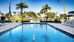 A swimming pool with lounge chairs and palm trees.