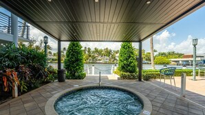 A hot tub area with a view of a body of water and palm trees.