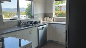 Une cuisine moderne avec des meubles blancs, un lave-vaisselle en acier inoxydable et un réfrigérateur noir.