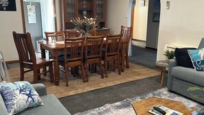 Un salon comprenant une table à manger, des chaises, un canapé, des poufs et une table basse.