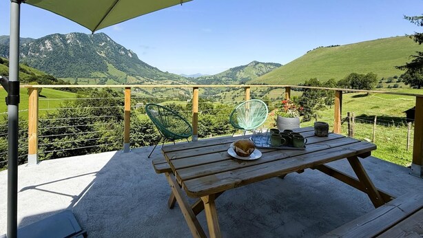 A wooden table with a picnic setup on a balcony overlooking a scenic mountain landscape. - GLIGET - LOURDIOS ICHERE (LOURDIOS ICHERE)