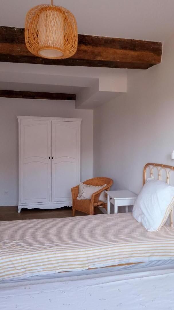 Un dormitorio con cama, una silla, una mesita y un armario.