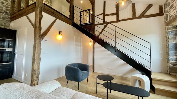 A loft-style living area with exposed wooden beams, a staircase, a sofa, a chair, and a small table. - HARRIA - SAINT-PEE-SUR-NIVELLE (SAINT-PEE-SUR-NIVELLE)