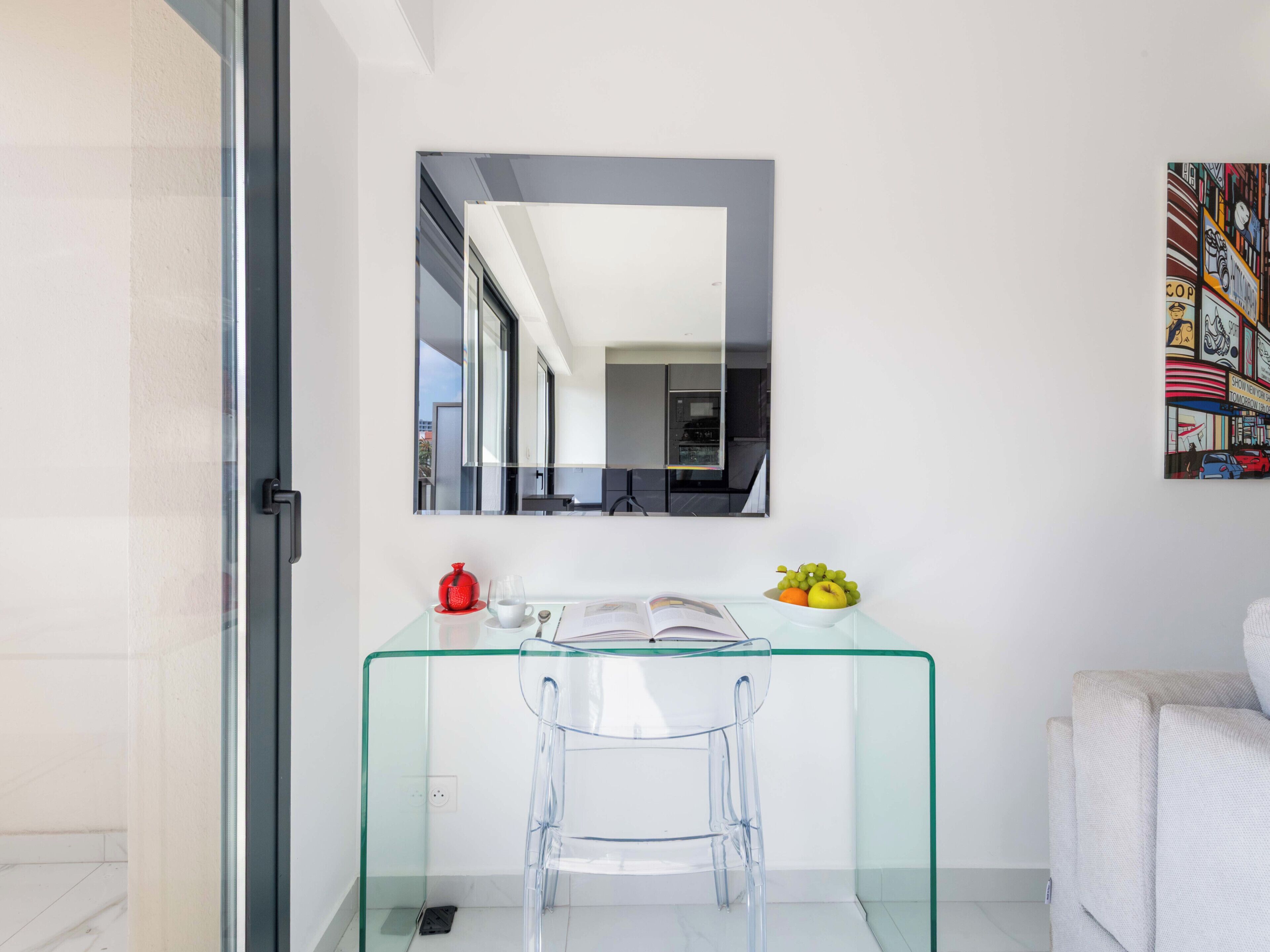 Een moderne badkamer met een glazen wastafel, een spiegel en een schaal fruit.