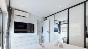 A modern hotel room with a large bed, a flat-screen TV mounted on the wall, and a sliding glass door leading to a balcony. - Central 1-Br with Balcony – Rue d’Antibes, Cannes (Cannes)