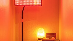 Een hoekje met een vloerlamp, een zoutlamp, een klein plankje met potplanten, en een lijst met een bericht aan de muur.