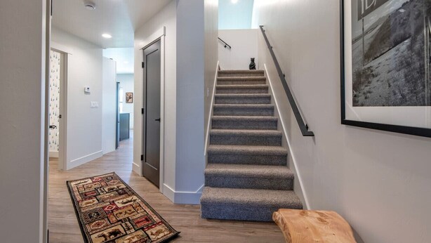 A modern interior with a carpeted staircase, a wooden bench, and a framed welcome sign. - Stone Peak Lodge w/ air conditioning (Driggs)