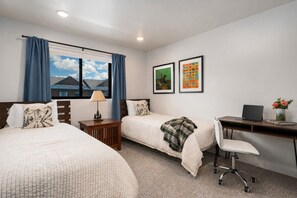 A hotel room with two beds, a desk, a chair, and a window with curtains. - Stone Peak Lodge w/ air conditioning (Driggs)