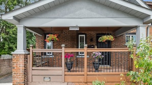 Un bâtiment en briques doté d’un porche, portant l’inscription « ORA’S PLACE BND », avec un panneau indiquant un espace de stationnement réservé aux visiteurs et des plantes en pot.