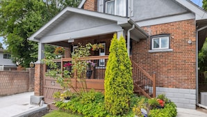 Une maison d’habitation avec une façade en briques, un porche abrité et un jardin bien entretenu.